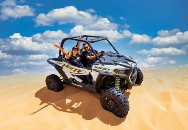 Polaris RZR 1000 two-seater dune buggy parked on a red dune ridge in Dubai